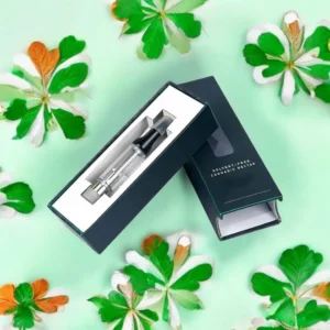 Premium CBD vape cartridge packaging in a sleek black and green box with a clear window, displayed against a vibrant green background with clover leaves.