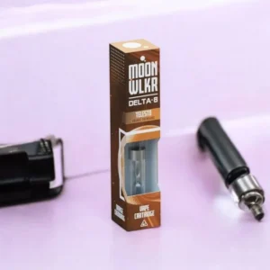 Brown custom vape cartridge box branded as "Moon WLKR Delta-8" with a clear window, placed on a pastel purple surface with a vape device nearby.