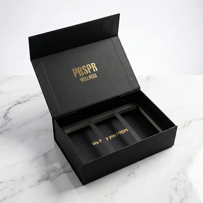 Black magnetic rigid box with gold foil branding and magnetic closure on a dark marble countertop