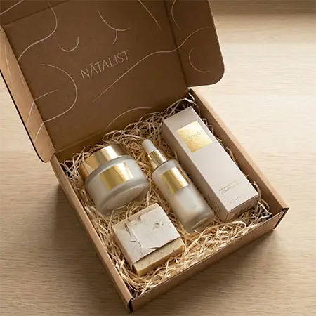 Custom kraft mailer box with premium glass skincare bottles and gold-foil labels for cosmetic brands.